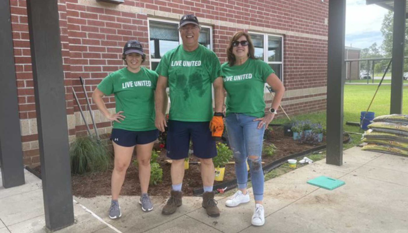 member's of the kaiser vacation rental team in matching tee shirts standing in front of plants at elementary school