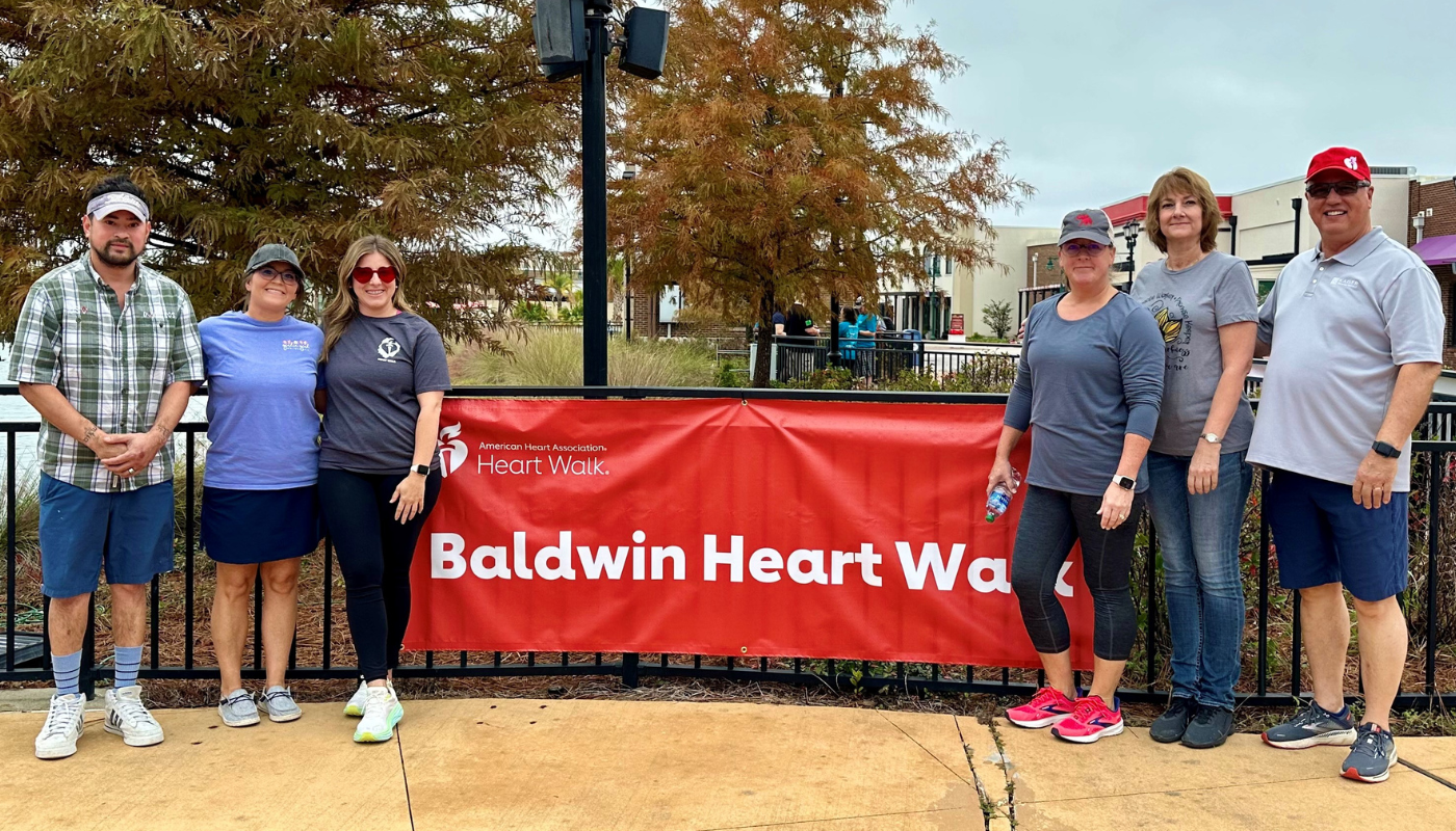the kaiser vacation rentals team standing in front of a baldwin heart walk banner 